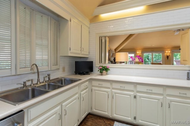 kitchen featuring sink, white cabinetry, dishwasher, vaulted ceiling, and backsplash