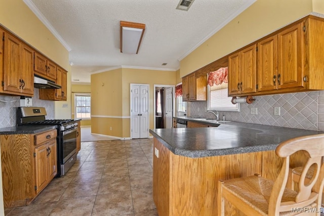 kitchen with stainless steel appliances, a kitchen bar, a textured ceiling, and kitchen peninsula