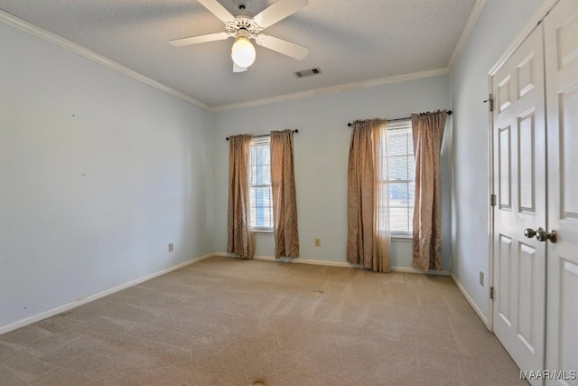 carpeted spare room with ceiling fan, ornamental molding, and a textured ceiling