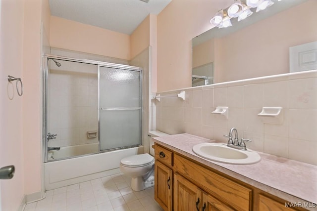 full bathroom with toilet, tile walls, shower / bath combination with glass door, backsplash, and vanity