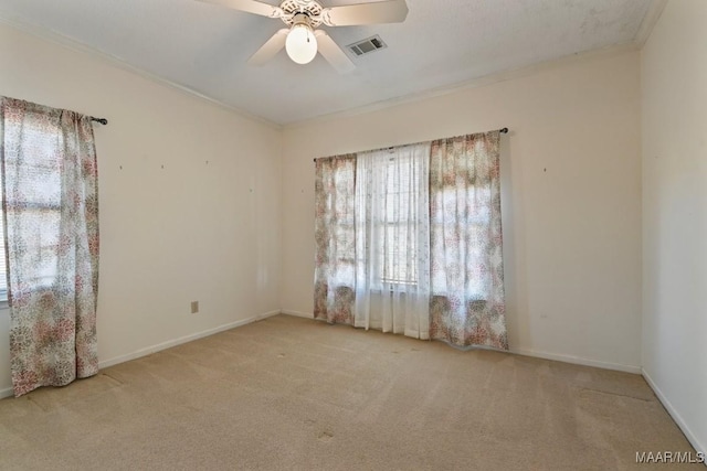 carpeted spare room with ceiling fan, a healthy amount of sunlight, and crown molding