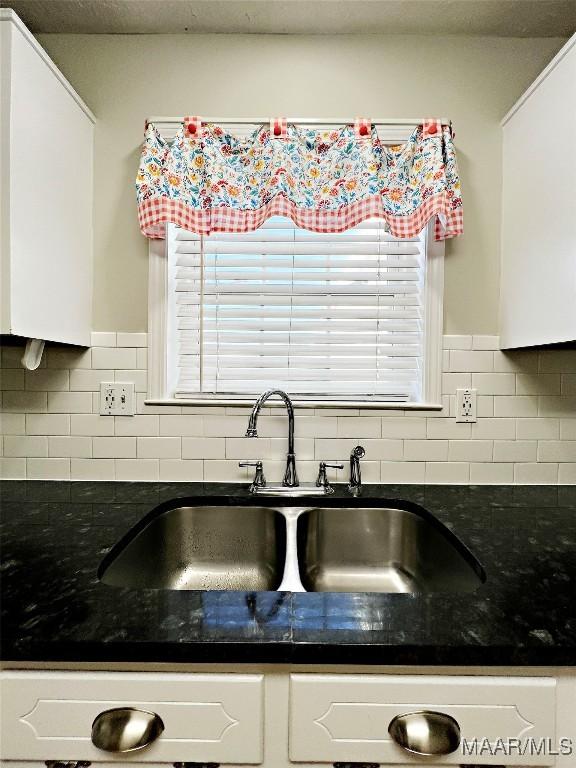 kitchen with sink, white cabinets, tasteful backsplash, and dark stone counters