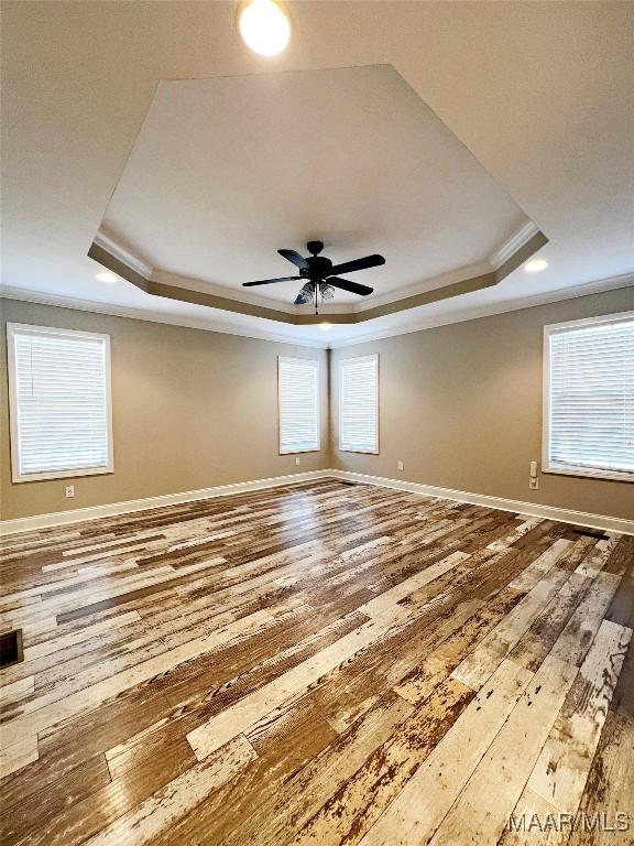 empty room featuring hardwood / wood-style flooring, ceiling fan, and a tray ceiling