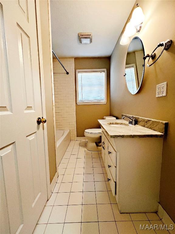 full bathroom with toilet, tile patterned flooring, vanity, and tiled shower / bath