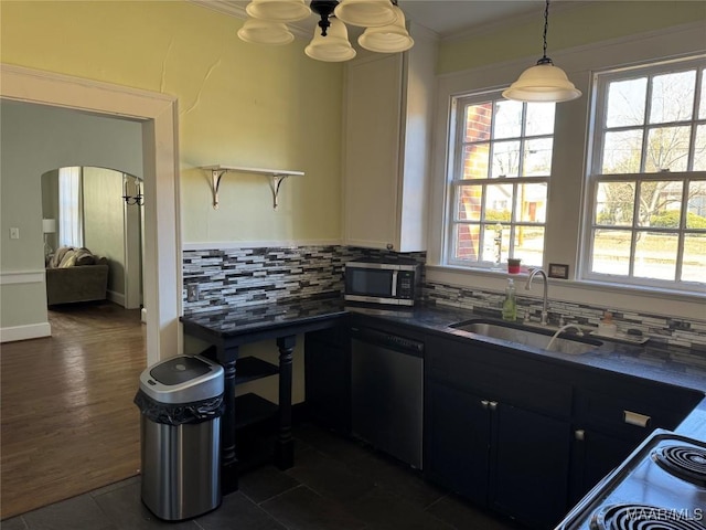 kitchen with dark tile patterned floors, appliances with stainless steel finishes, tasteful backsplash, hanging light fixtures, and sink