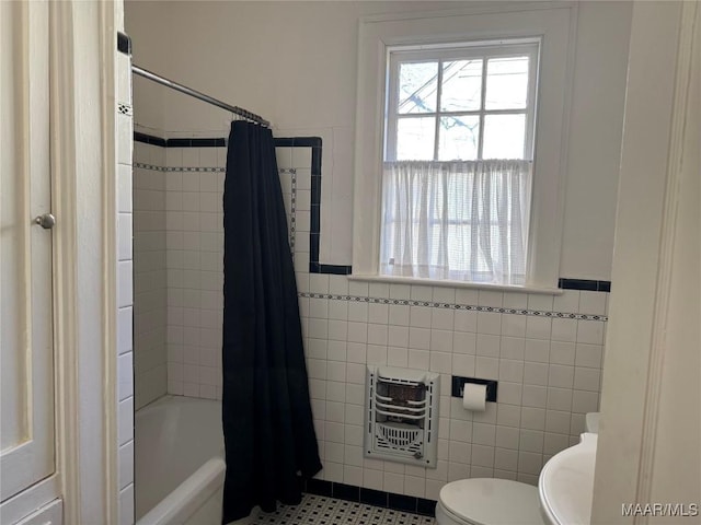 bathroom featuring toilet, shower / bath combo with shower curtain, tile walls, heating unit, and tile patterned floors