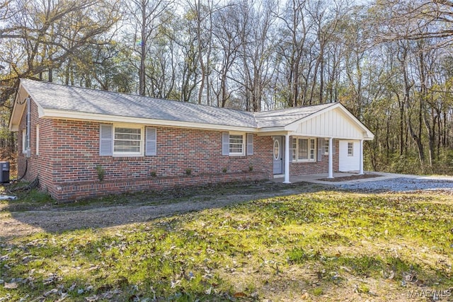 single story home with a front yard, covered porch, brick siding, and cooling unit