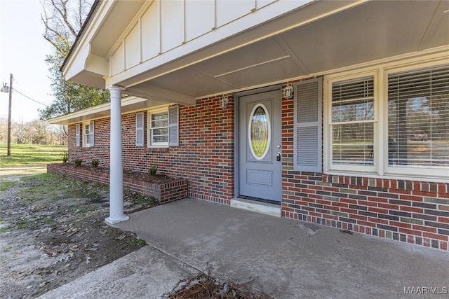 view of exterior entry featuring board and batten siding and brick siding