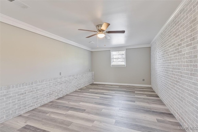 unfurnished room featuring light wood finished floors, brick wall, ceiling fan, and crown molding