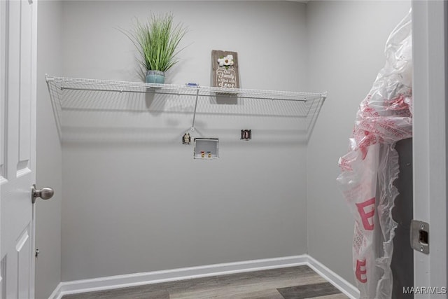 clothes washing area with laundry area, wood finished floors, hookup for a washing machine, and baseboards