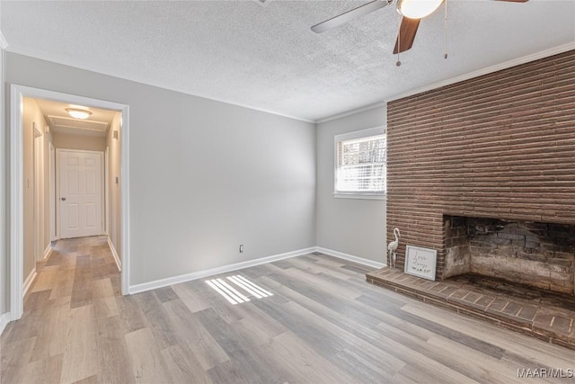 unfurnished living room with baseboards, a fireplace, a textured ceiling, and light wood finished floors