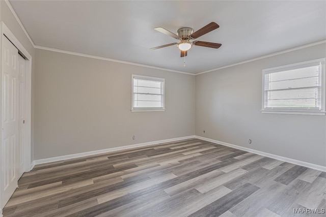 interior space featuring baseboards, a ceiling fan, crown molding, light wood-style floors, and a closet