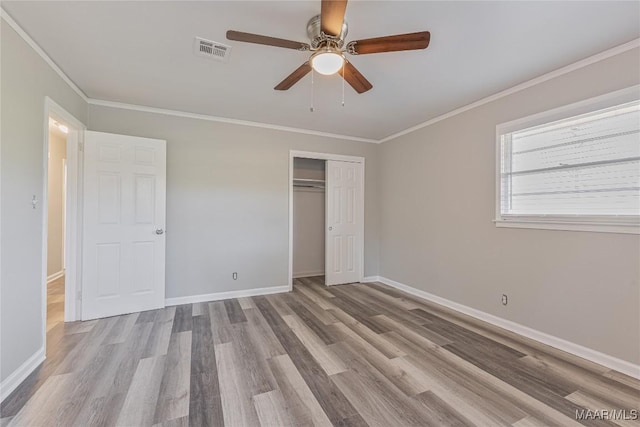 unfurnished bedroom with light wood-type flooring, visible vents, crown molding, and baseboards