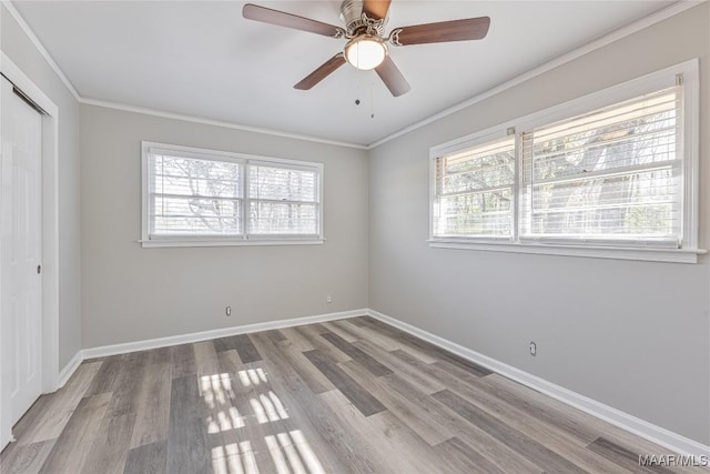 unfurnished bedroom featuring ceiling fan, baseboards, ornamental molding, a closet, and light wood-type flooring