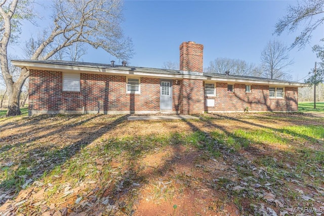 rear view of house featuring a yard, brick siding, and a chimney