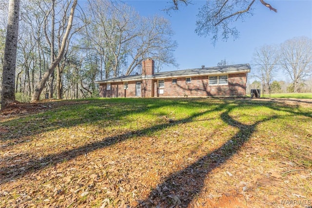 view of front facade featuring a chimney, a front lawn, and brick siding