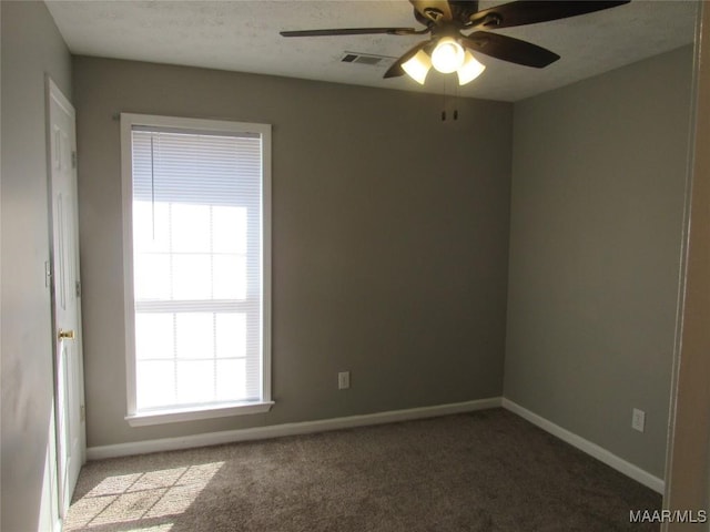 unfurnished room with a ceiling fan, carpet, visible vents, baseboards, and a textured ceiling