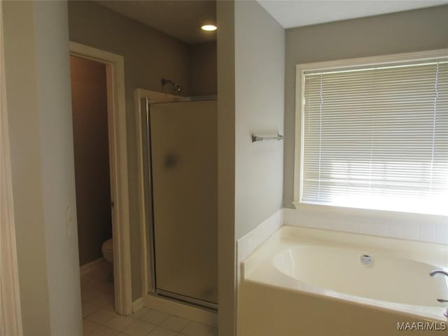 full bathroom featuring tile patterned flooring, a stall shower, toilet, and a garden tub