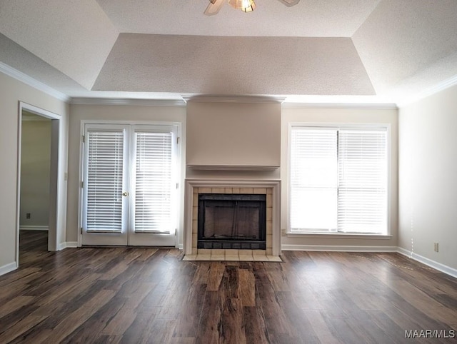 unfurnished living room with ceiling fan, a wealth of natural light, dark hardwood / wood-style flooring, and a tray ceiling