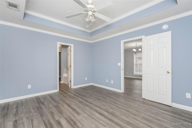 spare room featuring a textured ceiling, a raised ceiling, hardwood / wood-style floors, ceiling fan with notable chandelier, and ornamental molding