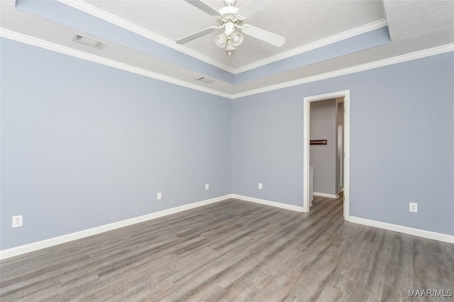 unfurnished room featuring hardwood / wood-style flooring, a textured ceiling, a raised ceiling, ceiling fan, and ornamental molding