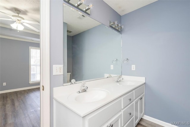 bathroom featuring toilet, wood-type flooring, vanity, ceiling fan, and a textured ceiling