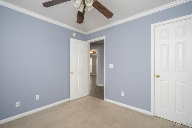 carpeted empty room featuring ceiling fan and crown molding