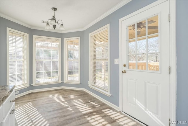 entryway with ornamental molding and an inviting chandelier