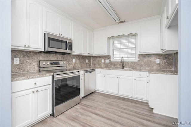 kitchen featuring appliances with stainless steel finishes, light hardwood / wood-style flooring, white cabinets, and sink