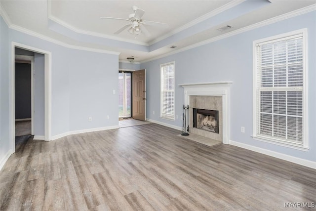 unfurnished living room featuring a raised ceiling, a fireplace, ceiling fan, and crown molding