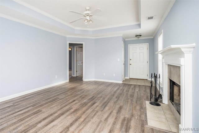 unfurnished living room with ceiling fan, light wood-type flooring, ornamental molding, and a tray ceiling