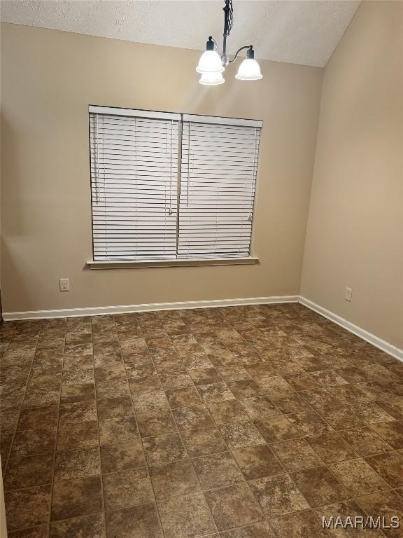 unfurnished room featuring a textured ceiling and an inviting chandelier