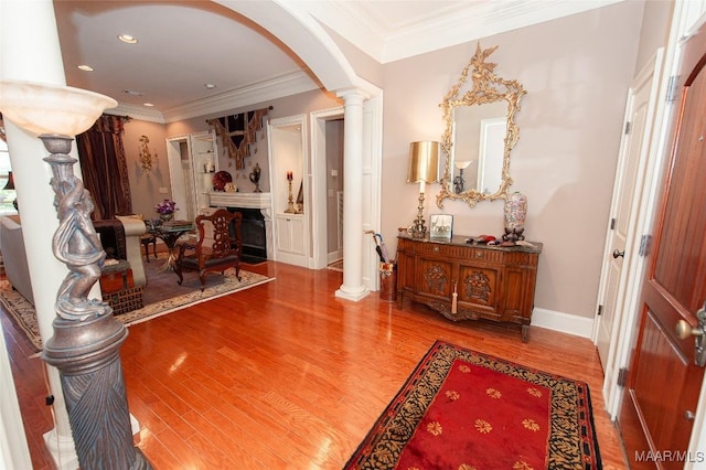 hallway with ornamental molding, hardwood / wood-style flooring, and decorative columns