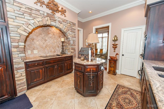 kitchen with black electric stovetop, light stone counters, ornamental molding, and a center island