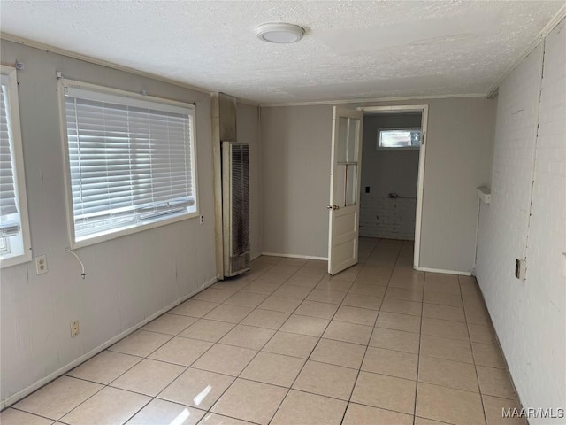 tiled spare room featuring a textured ceiling and ornamental molding