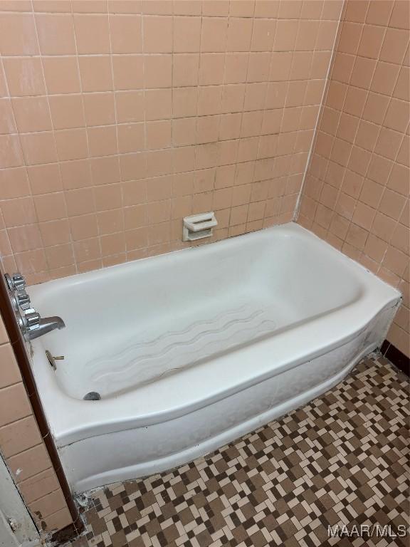 bathroom with tile patterned floors and a bath