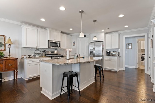 kitchen with backsplash, pendant lighting, white cabinetry, a kitchen island with sink, and stainless steel appliances