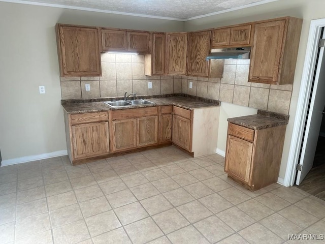 kitchen featuring a textured ceiling, tasteful backsplash, sink, ornamental molding, and light tile patterned flooring