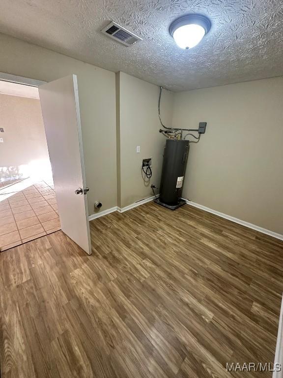 laundry room with water heater, a textured ceiling, and wood-type flooring