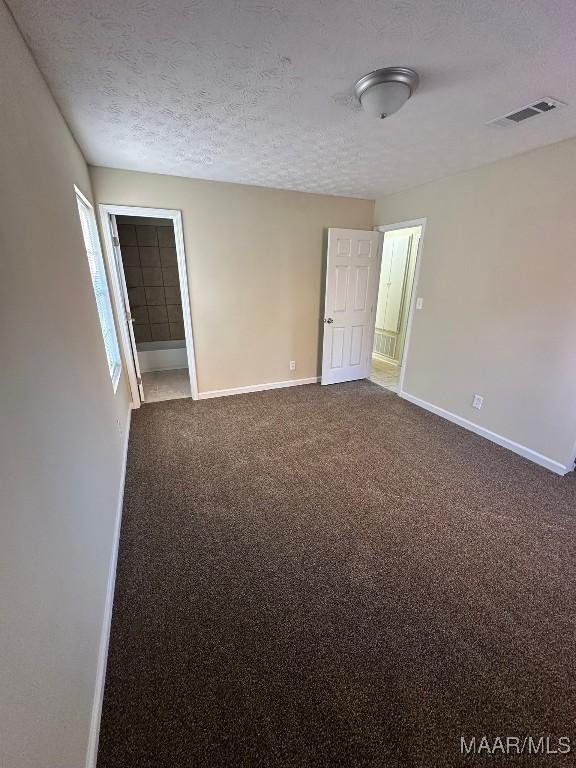 spare room with a textured ceiling and carpet floors