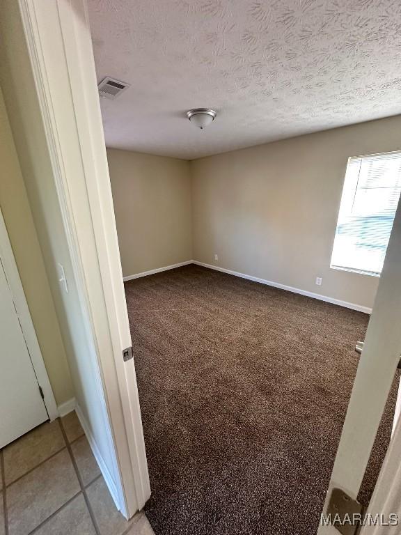 carpeted empty room featuring a textured ceiling