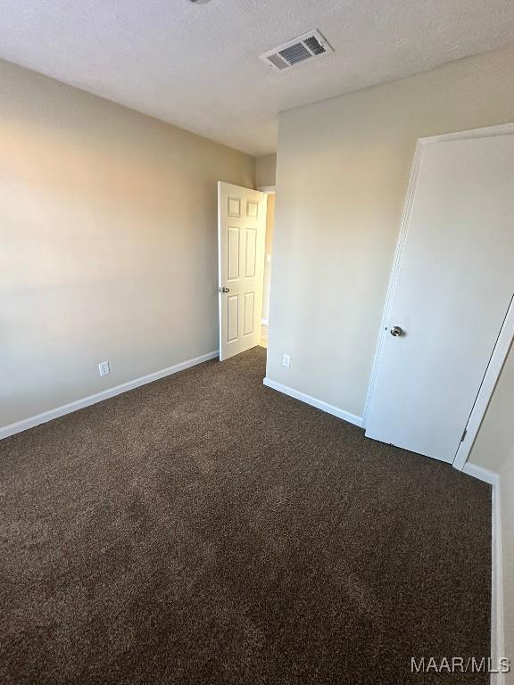 carpeted empty room with a textured ceiling