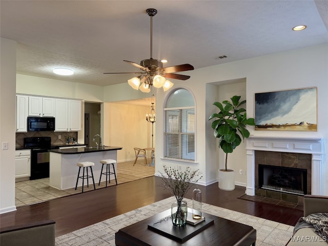 living room with light hardwood / wood-style floors, sink, and a tiled fireplace