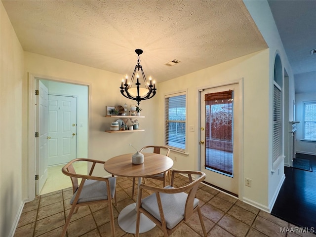 dining room featuring a wealth of natural light, tile patterned floors, a chandelier, and a textured ceiling