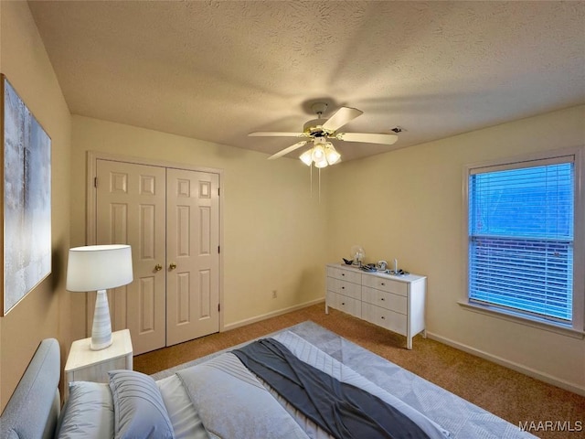 carpeted bedroom with ceiling fan, a textured ceiling, and a closet