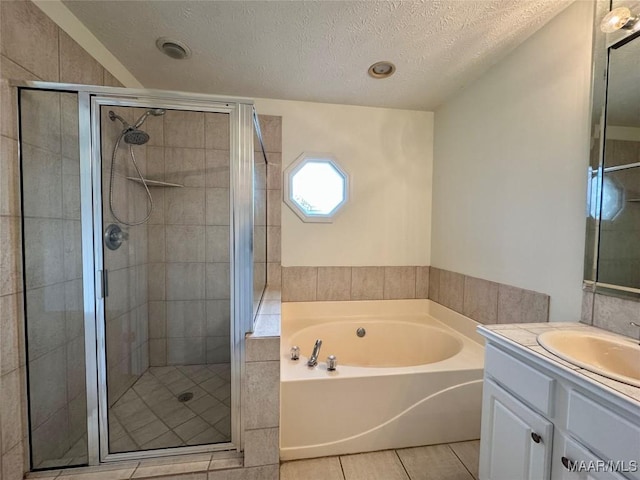 bathroom featuring a textured ceiling, tile patterned floors, separate shower and tub, and vanity