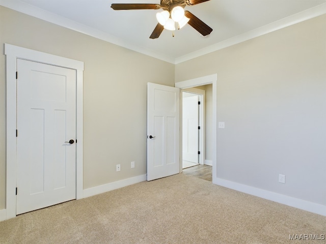 unfurnished bedroom featuring ceiling fan, light colored carpet, and crown molding