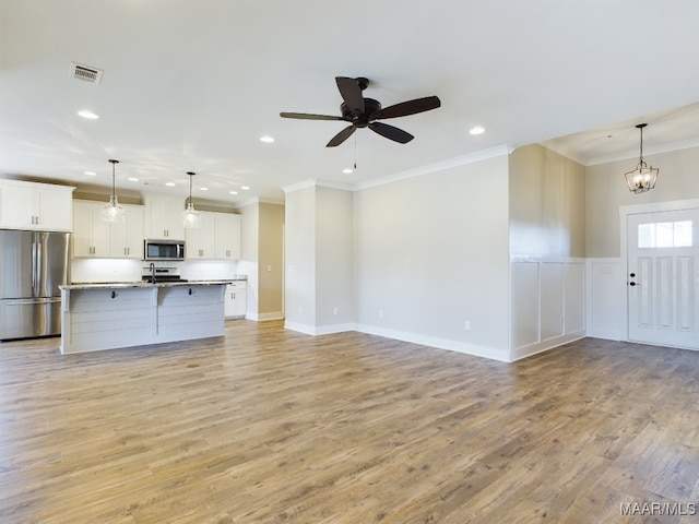 unfurnished living room featuring ceiling fan with notable chandelier, sink, light hardwood / wood-style flooring, and ornamental molding