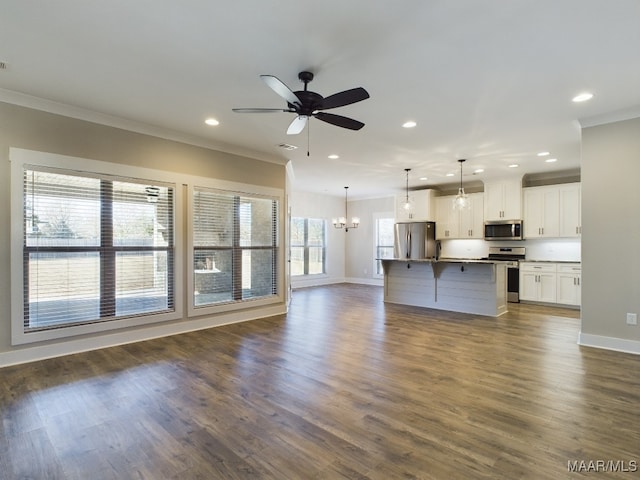 unfurnished living room with ceiling fan with notable chandelier, dark hardwood / wood-style floors, and crown molding