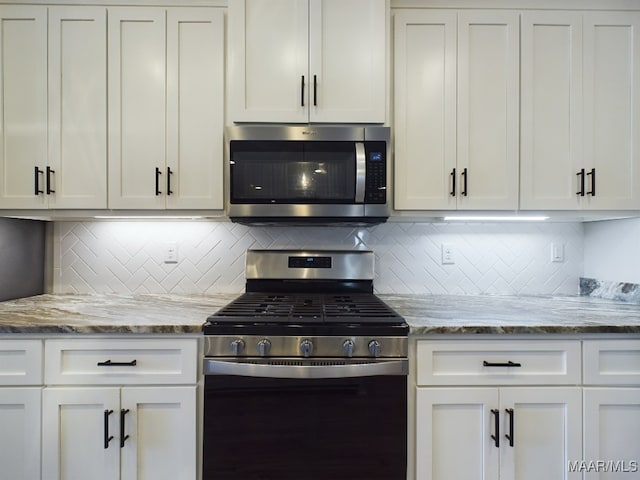 kitchen with white cabinetry, light stone counters, appliances with stainless steel finishes, and decorative backsplash